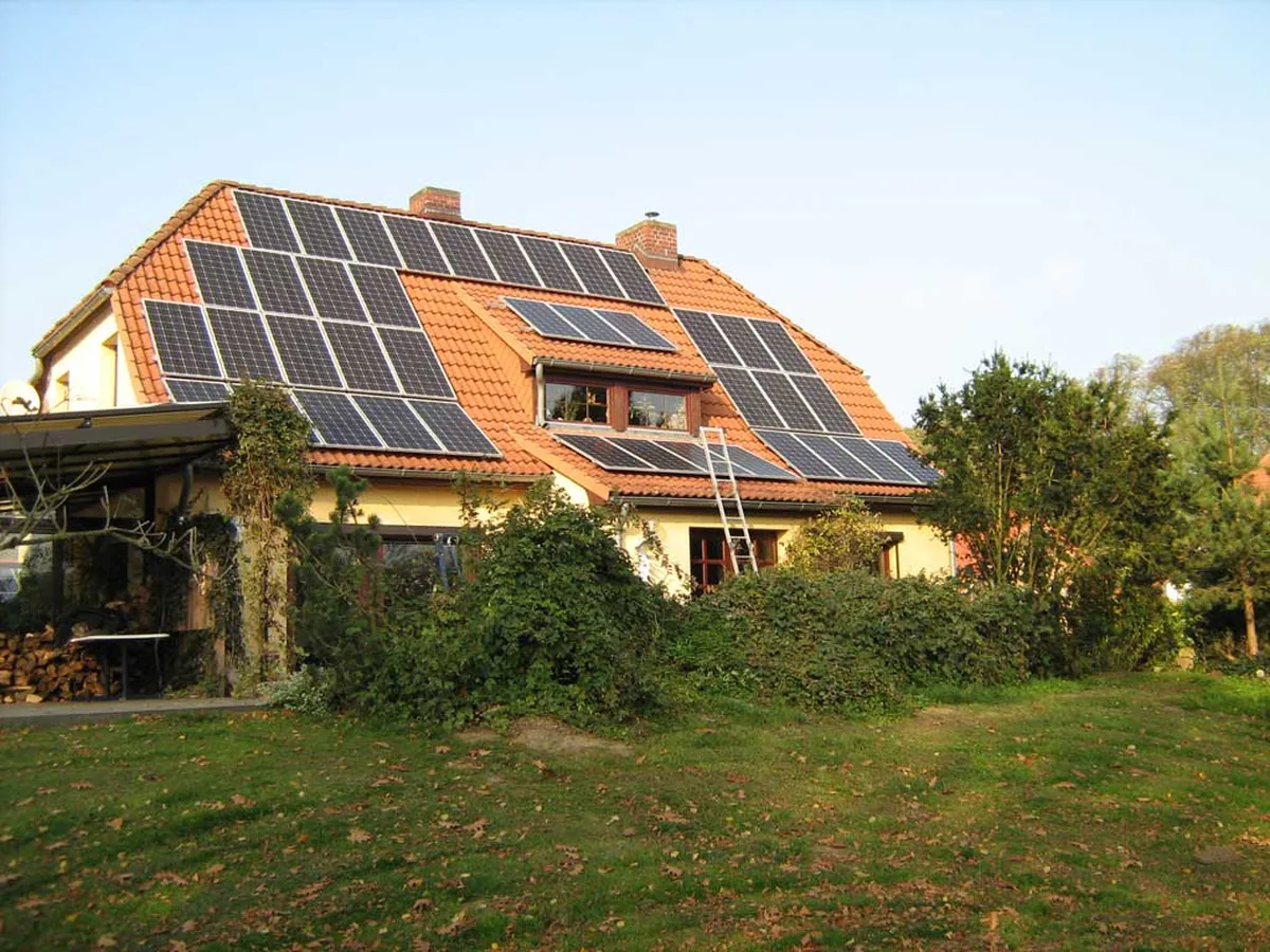 Wohnhaus mit vollständig belegtem Solardach und Holzstapel im Garten